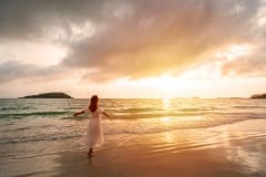 Young woman traveler looking beautiful sunset on the tranquil beach, Summer vacation concept